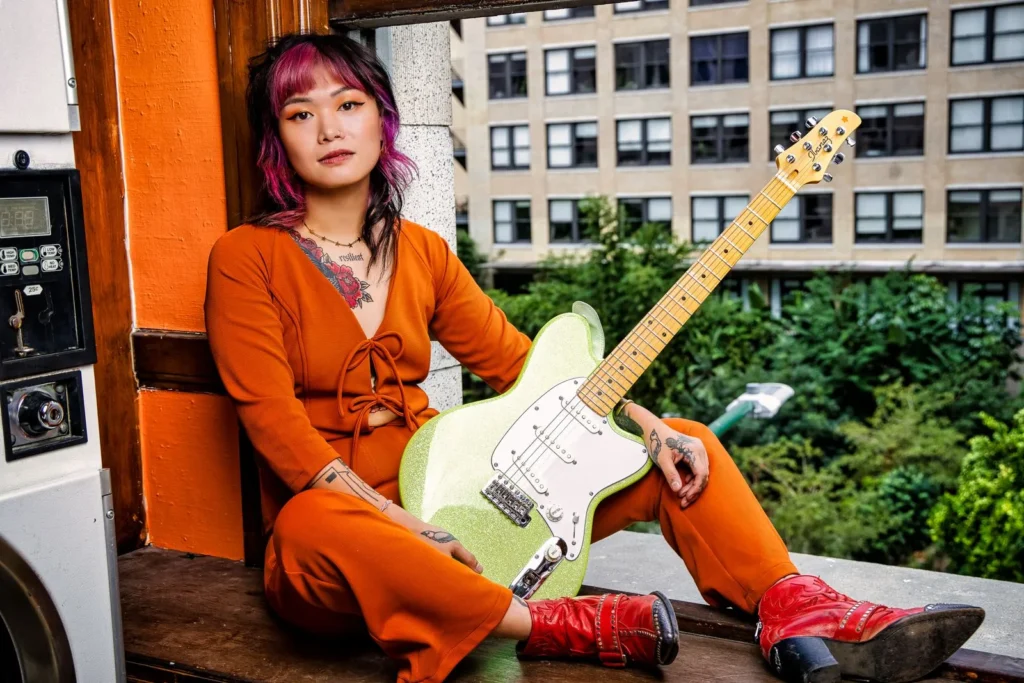a woman sitting on a window sill holding a guitar