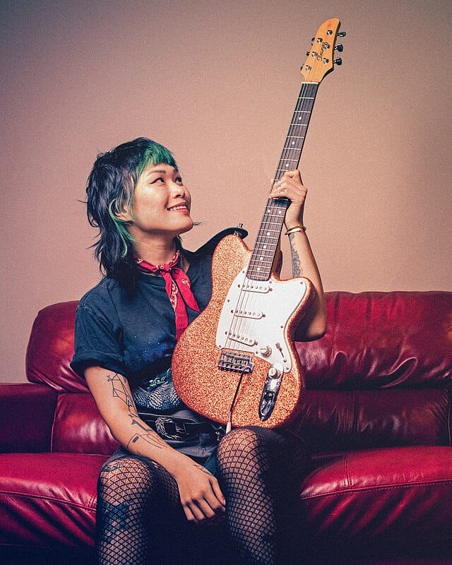 a woman sitting on a couch holding a guitar