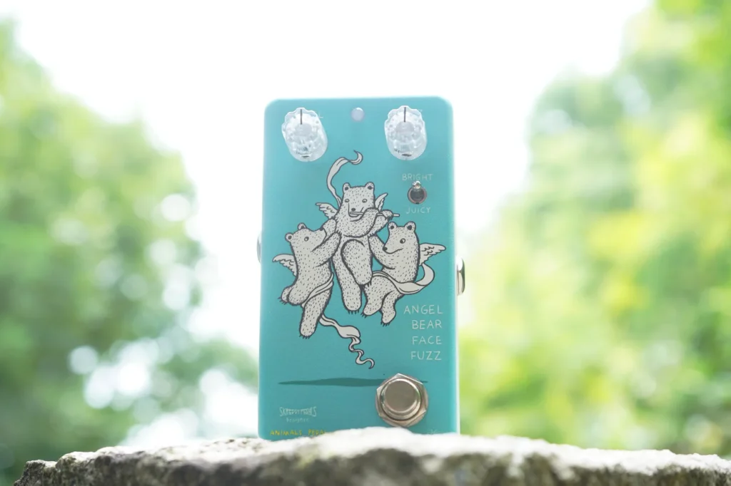 an animals pedal angel bear face fuzz pedal on a rock with a forest background