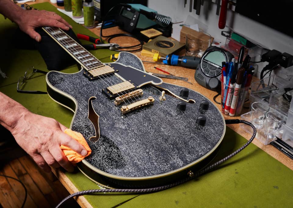 a person cleaning a d'angelico guitar