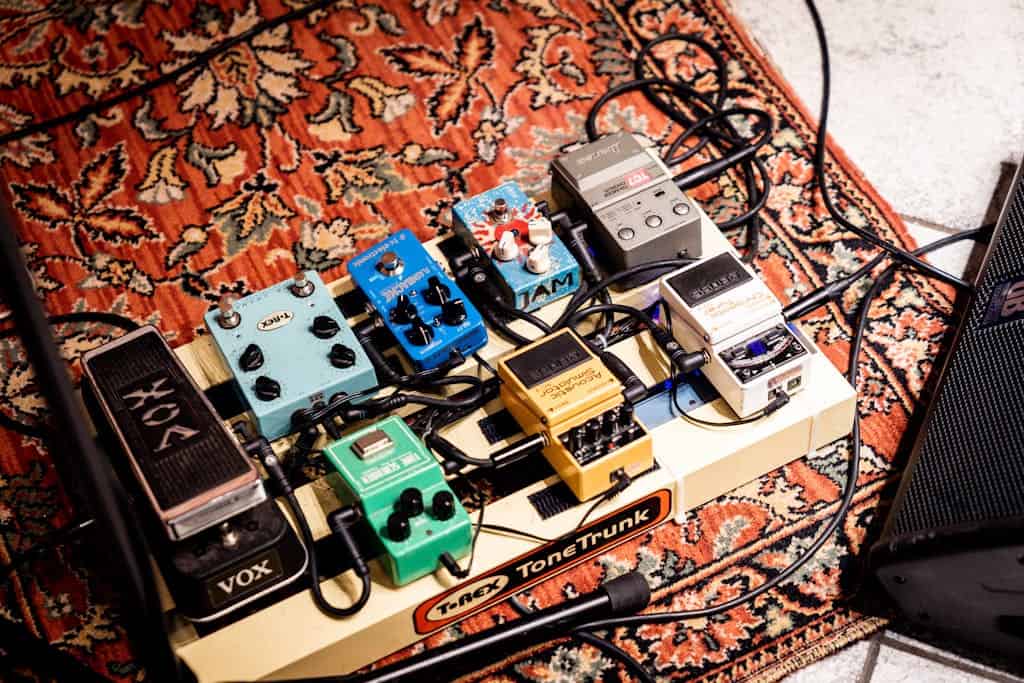 A vibrant display of guitar pedals on a patterned rug, highlighting music technology.