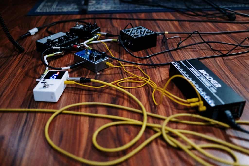 Close-up view of audio equipment and cables arranged on a wooden floor.