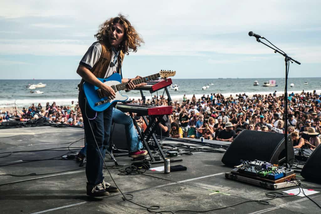 daniel donato playing guitar on stage in front of the ocean