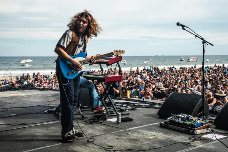 daniel donato playing guitar on stage in front of the ocean