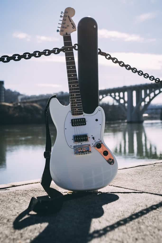 a white guitar leaning against a pole
